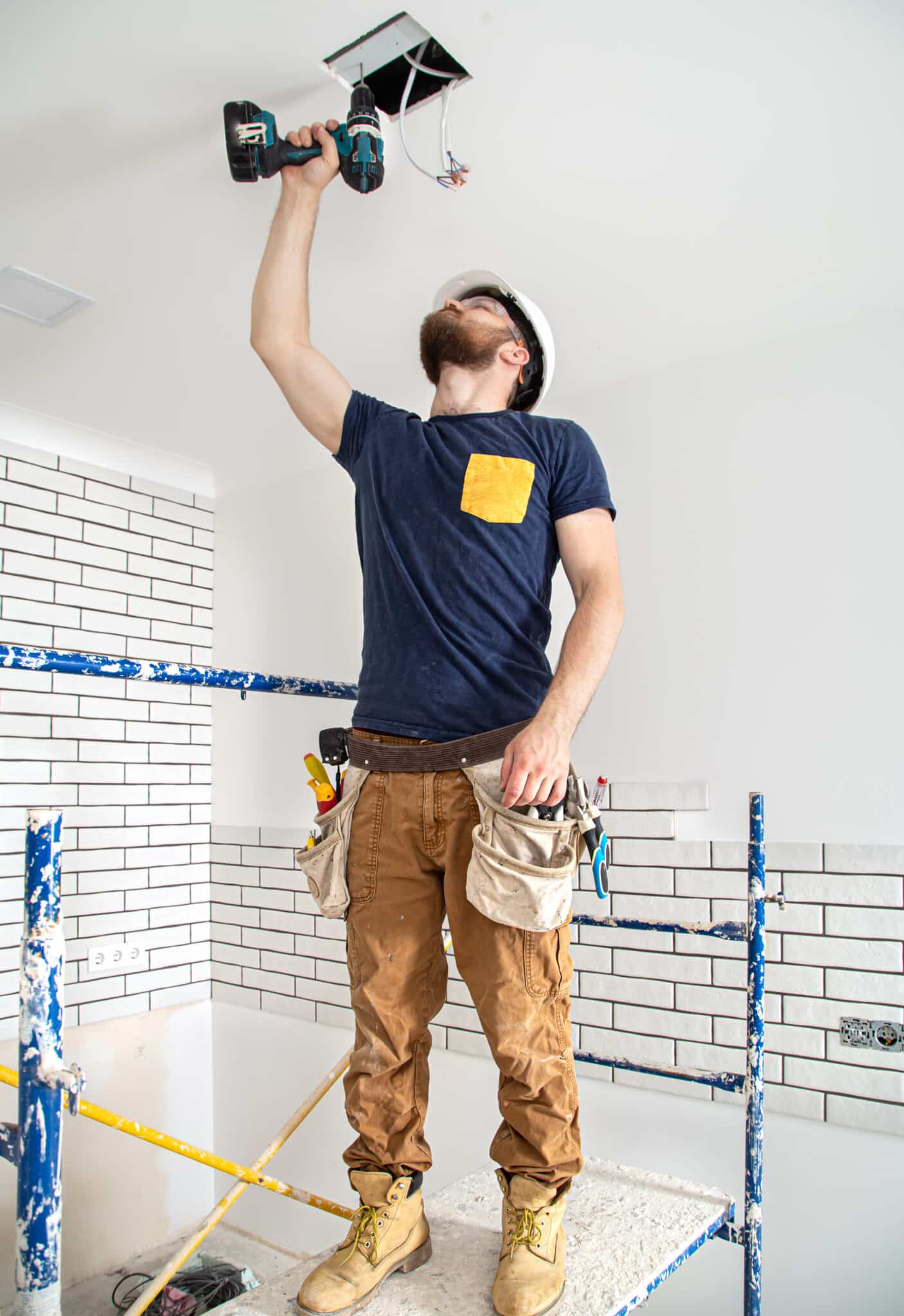 Électricien installant éclairage en hauteur