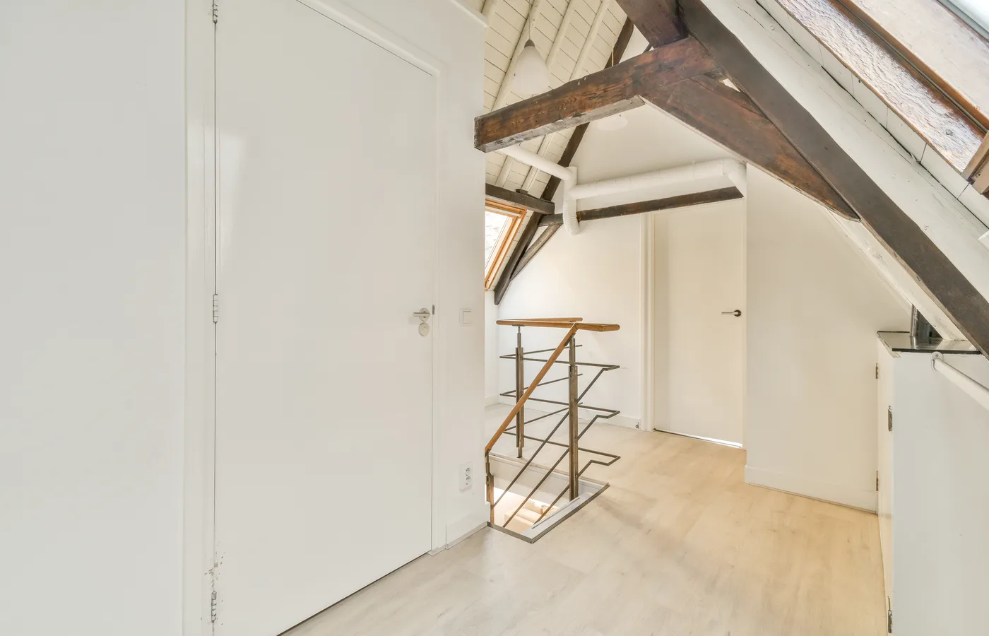 Combles aménagés et isolés, finitions en plaques de plâtre, poutres apparentes et parquet clair